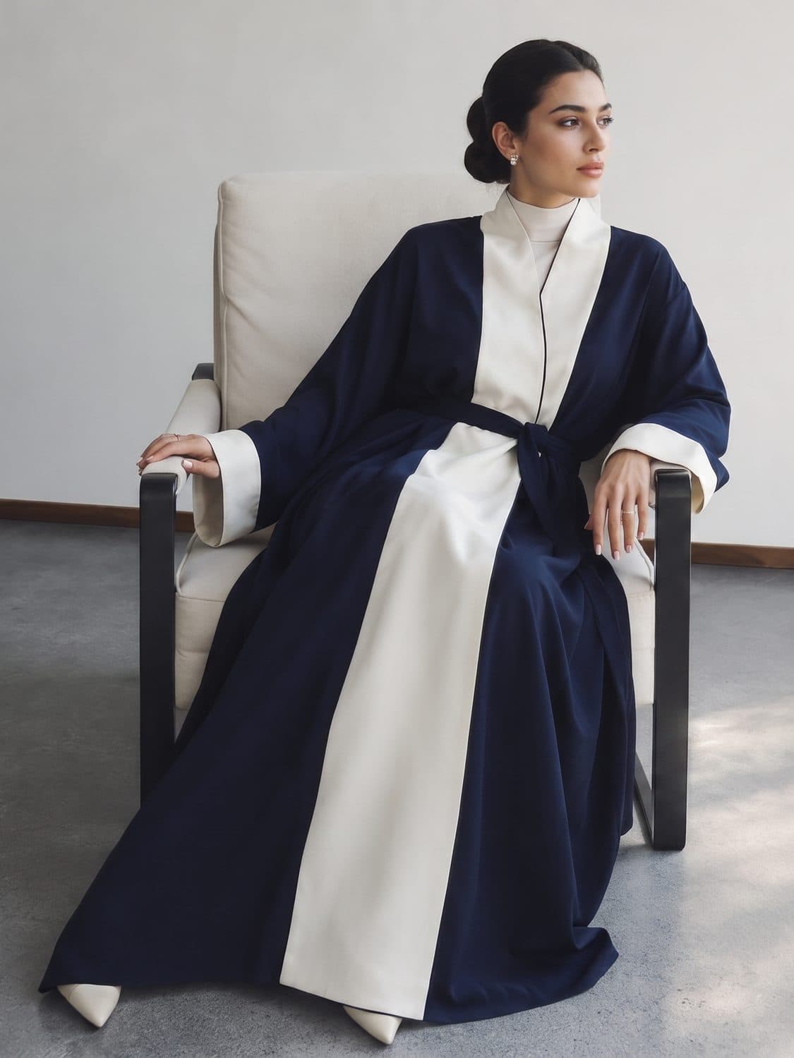 A navy and ivory belted abaya, seated in a still interior